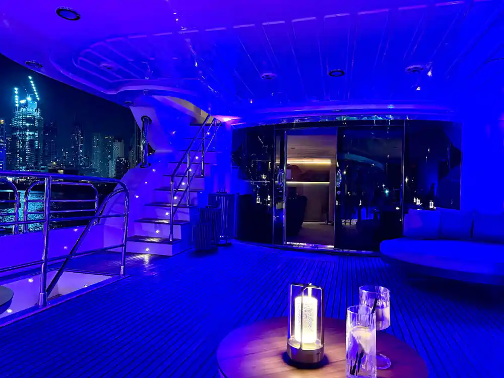 The aft deck lit blue at night with lanterns on the table
