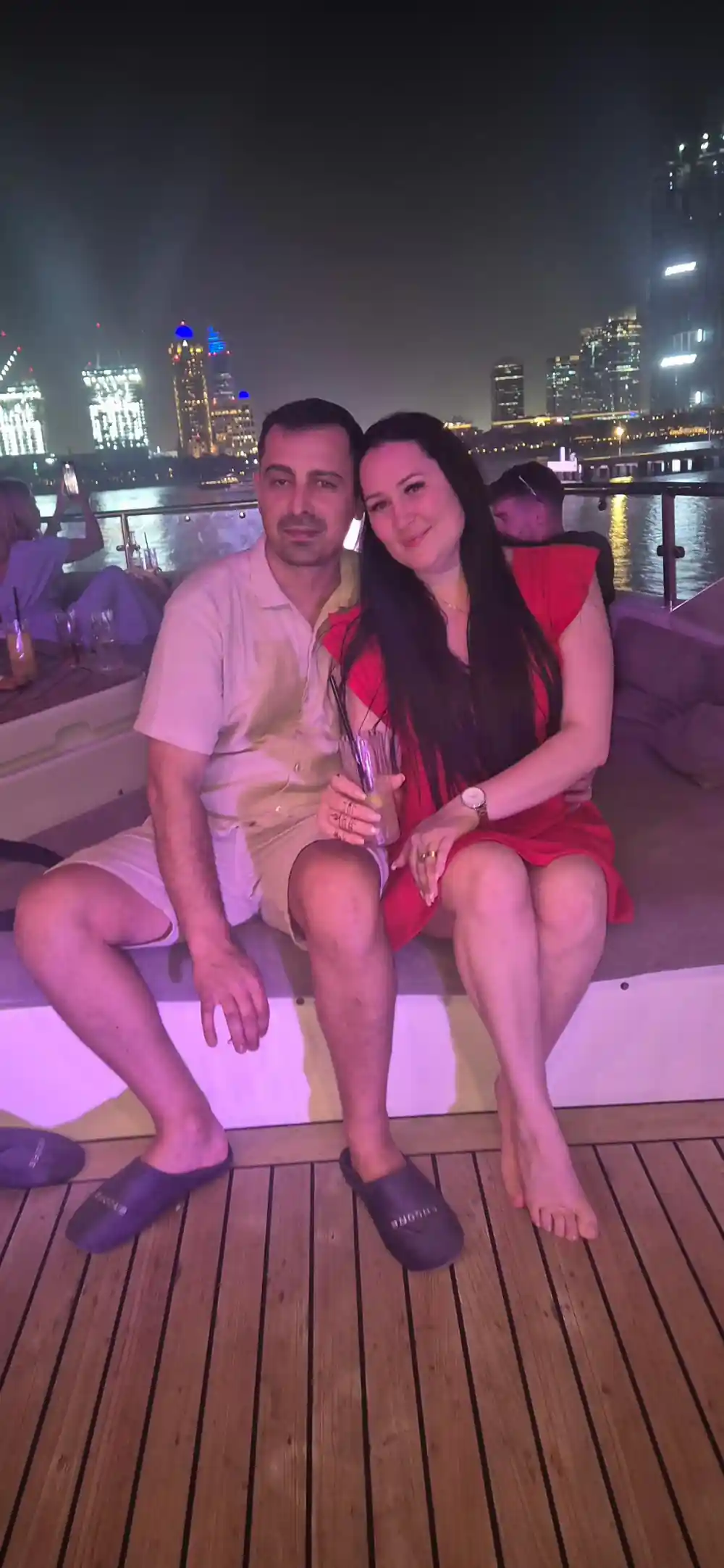 A couple seated on deck under purple light at night
