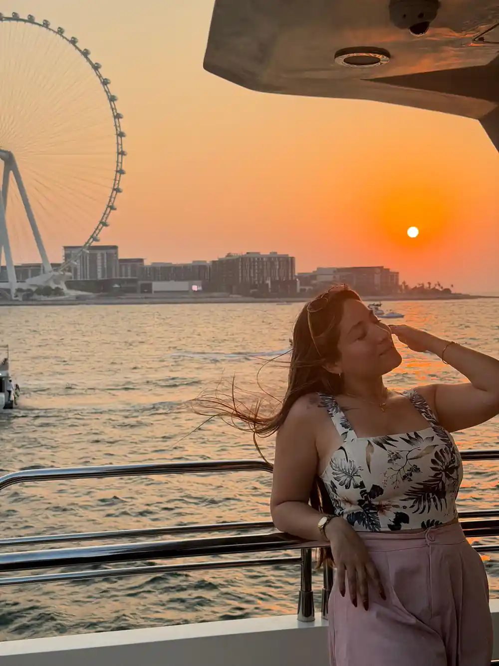 A guest on deck at sunset with the wheel behind