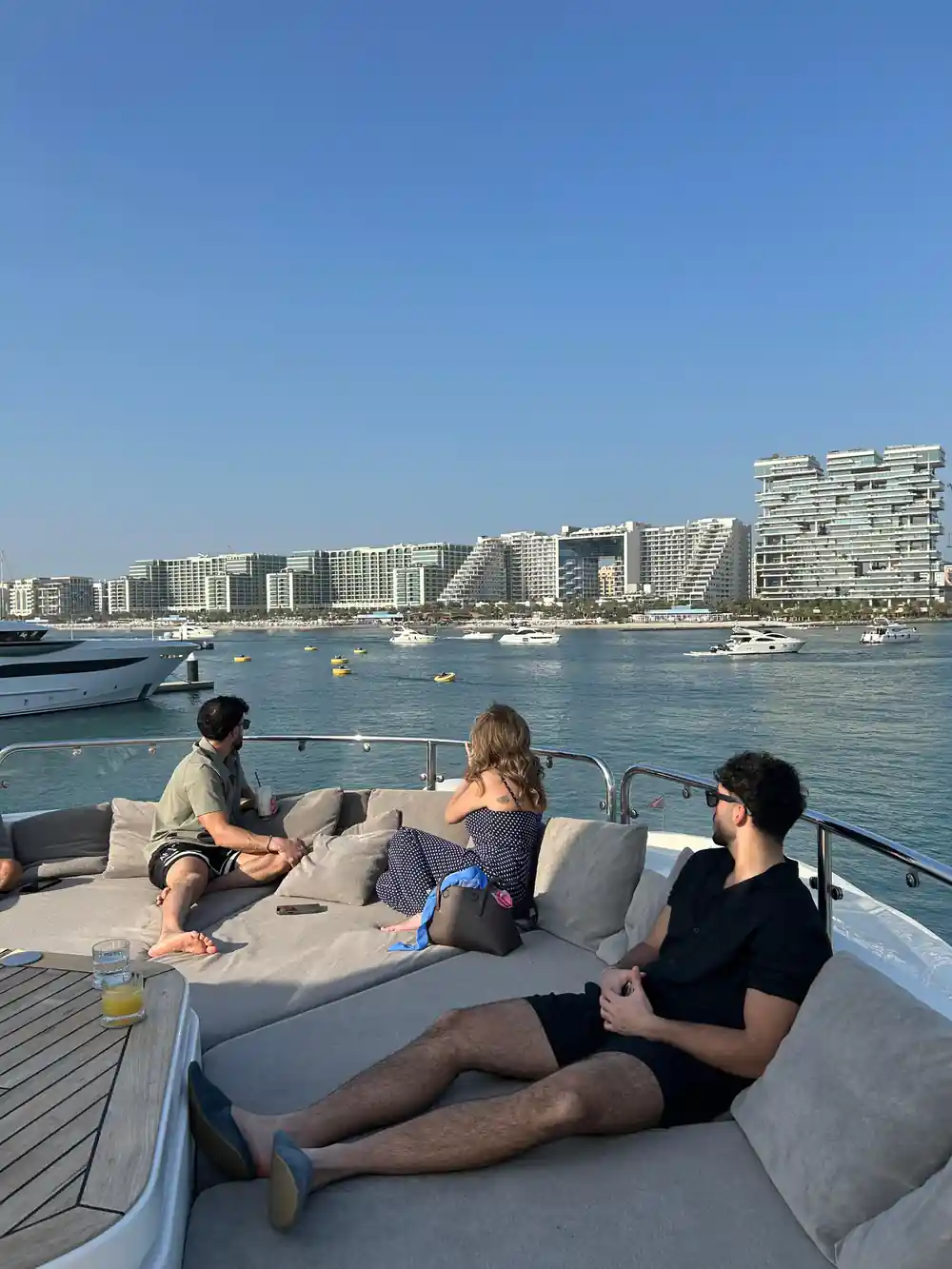Guests relaxing on deck cushions with the coast behind