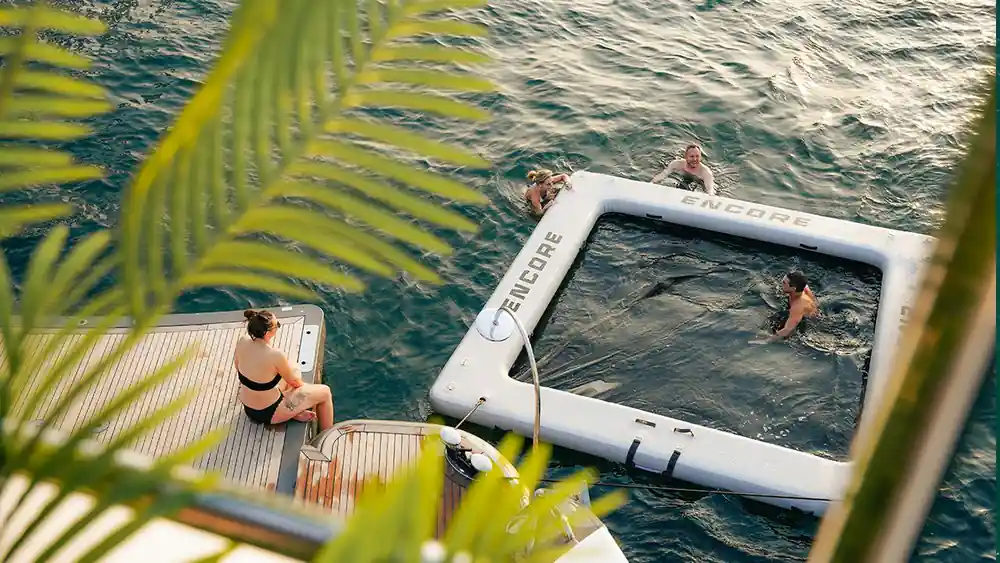 An inflatable floating platform in the water beside the yacht