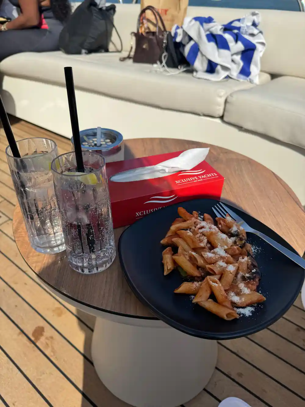 A plate of pasta and drinks on a deck table