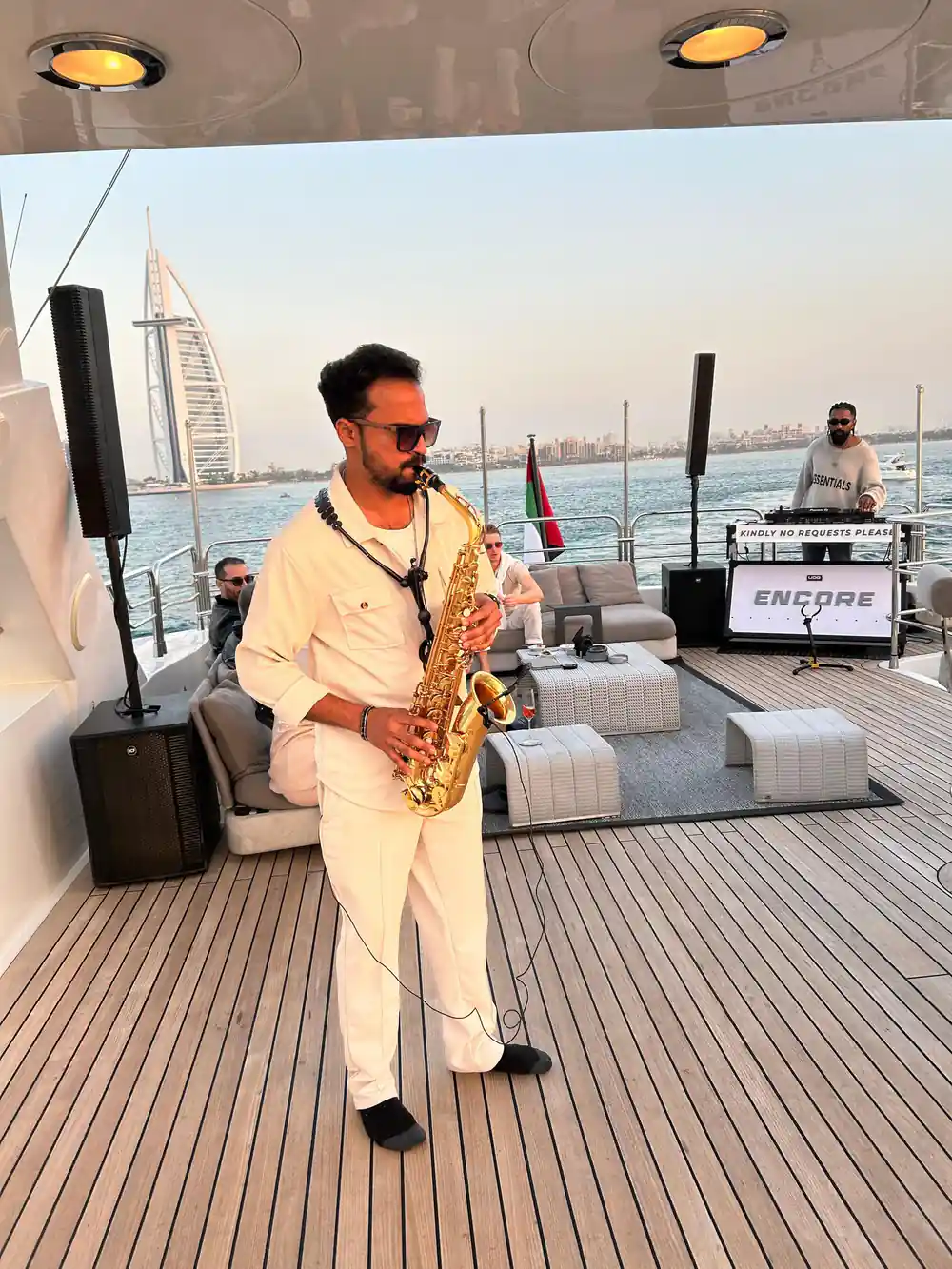 A saxophonist and DJ set up on the aft deck