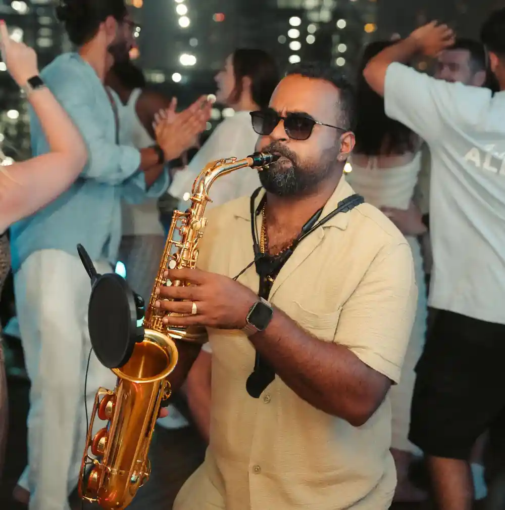 A saxophonist playing on deck among dancing guests