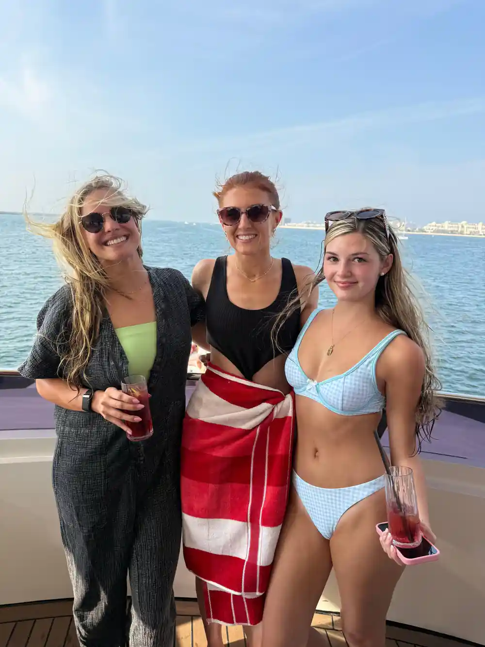 Three guests with drinks on the bow in swimwear