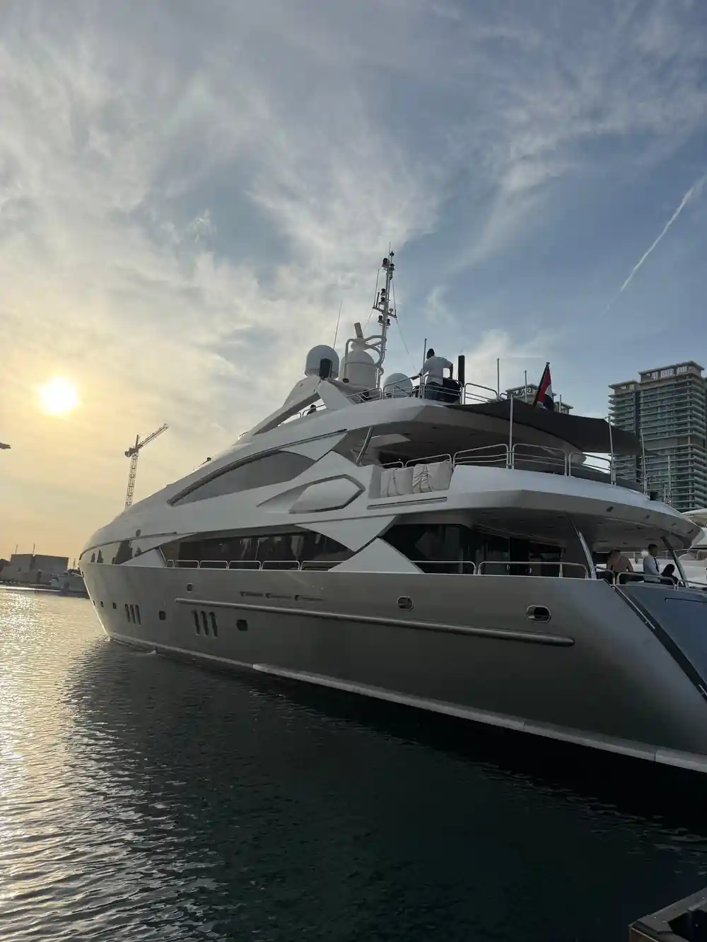 A yacht under a bright sun with the coast behind